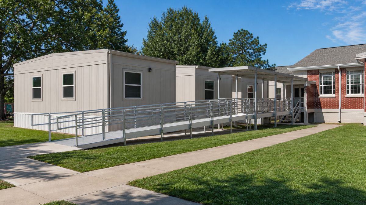 Row of portable classrooms with ADA ramps beside a public school campus